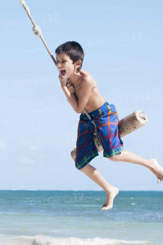 Hispanic boy playing on swing outdoors