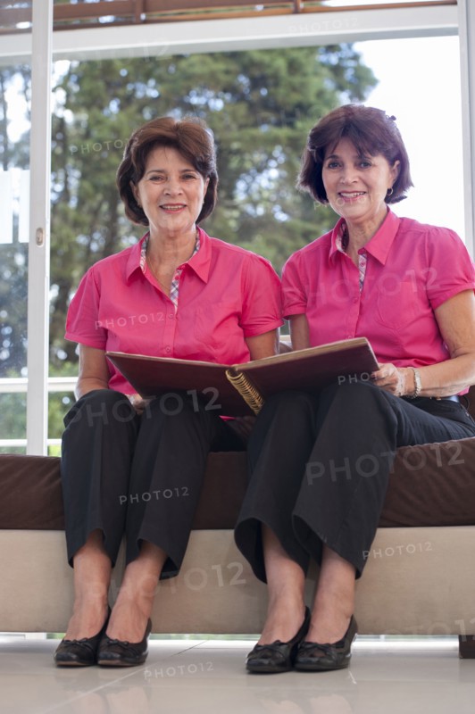 Senior Hispanic twins holding photograph album