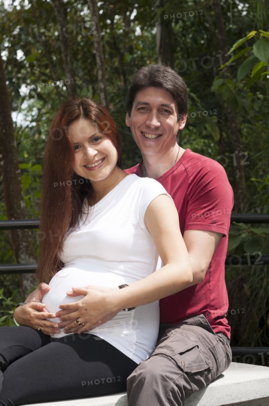 Mixed race expectant couple hugging outdoors