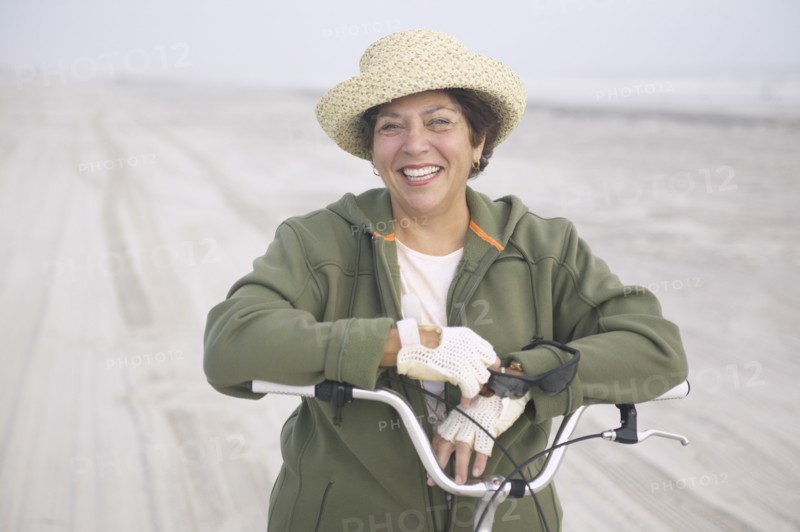 Senior woman with bicycle on beach