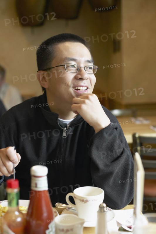 Asian man eating in restaurant