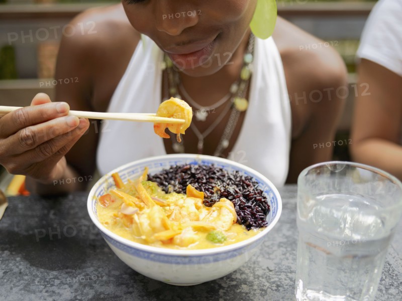 African woman eating Asian food in restaurant