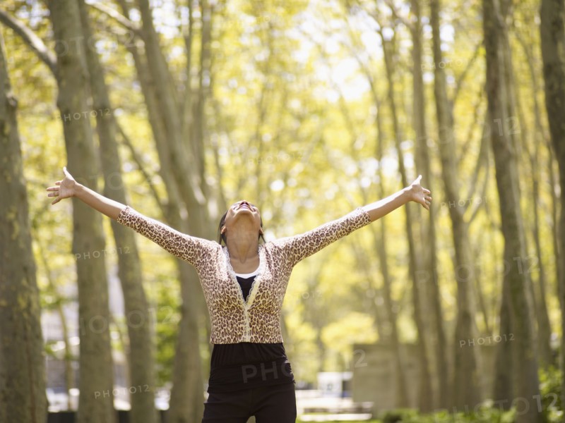 Mixed race woman with arms outstretched in park