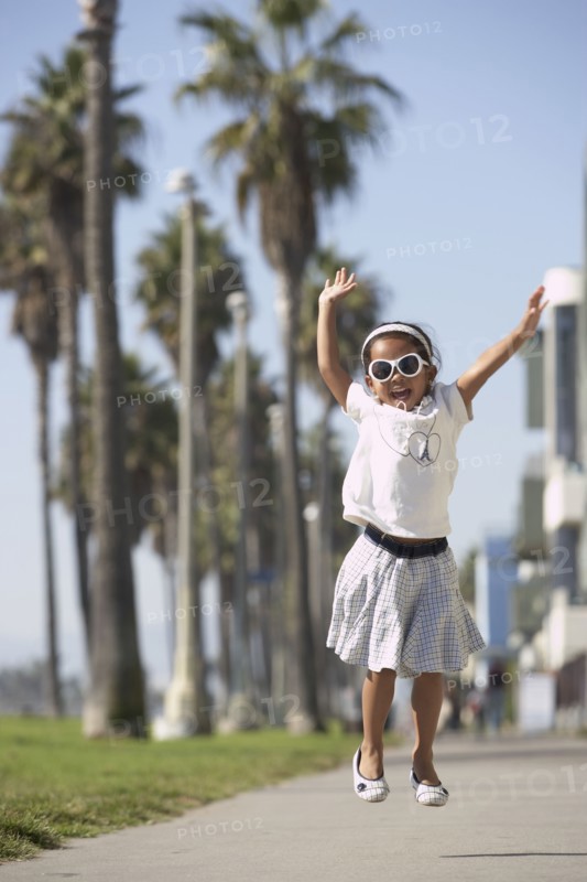 Young mixed race girl wearing sunglasses and jumping