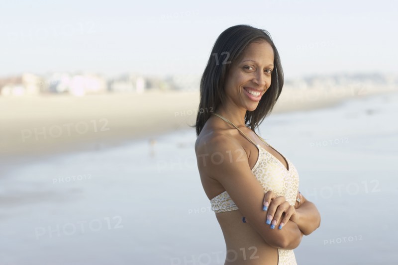 Mixed race woman with arms crossed at beach