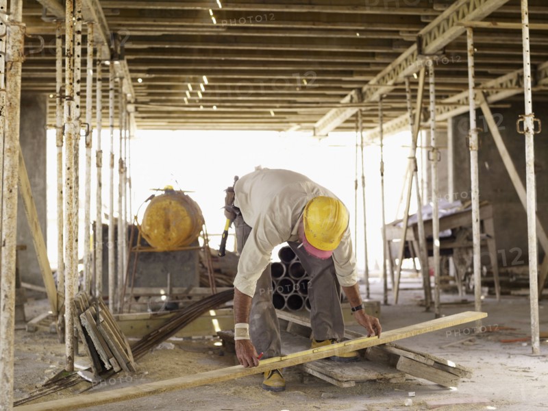Hispanic worker measuring lumber at construction site