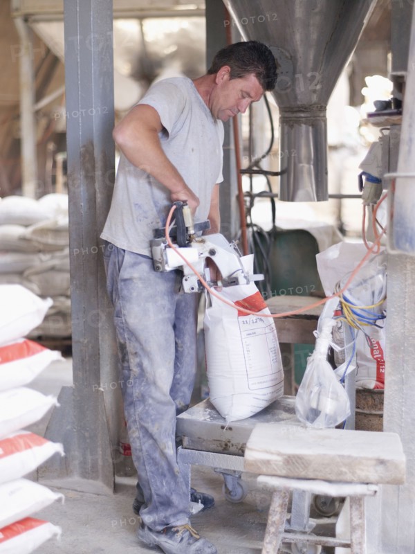 Hispanic worker sealing bag in factory warehouse