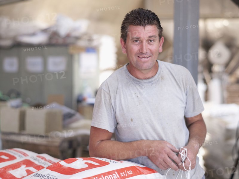 Hispanic worker holding bag in factory warehouse