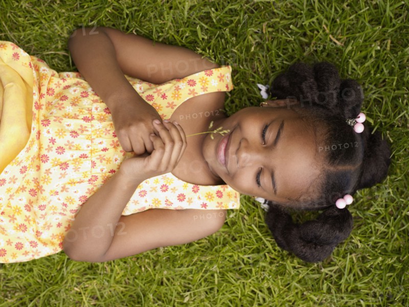 African girl laying in grass with eyes closed