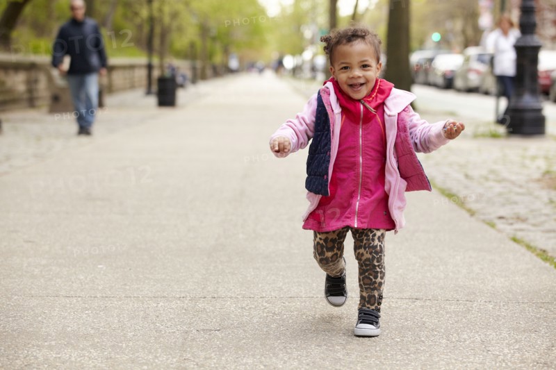 Mixed race baby girl walking on sidewalk