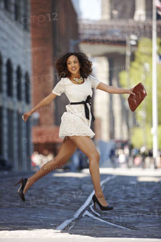 Glamorous mixed race woman running on urban street
