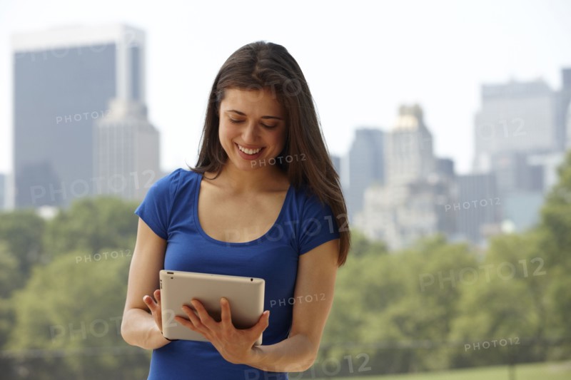 Caucasian woman using digital tablet in city park