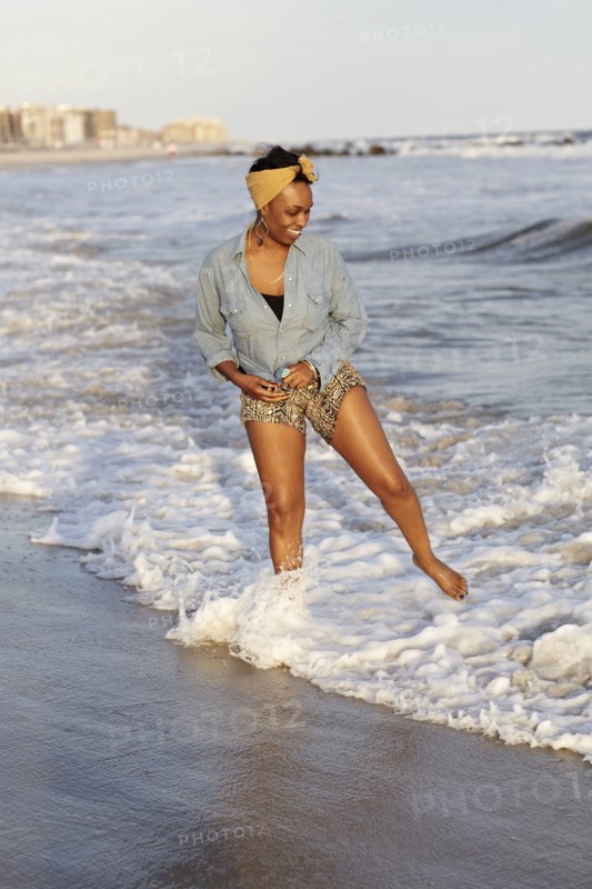 Black woman wading in ocean on beach