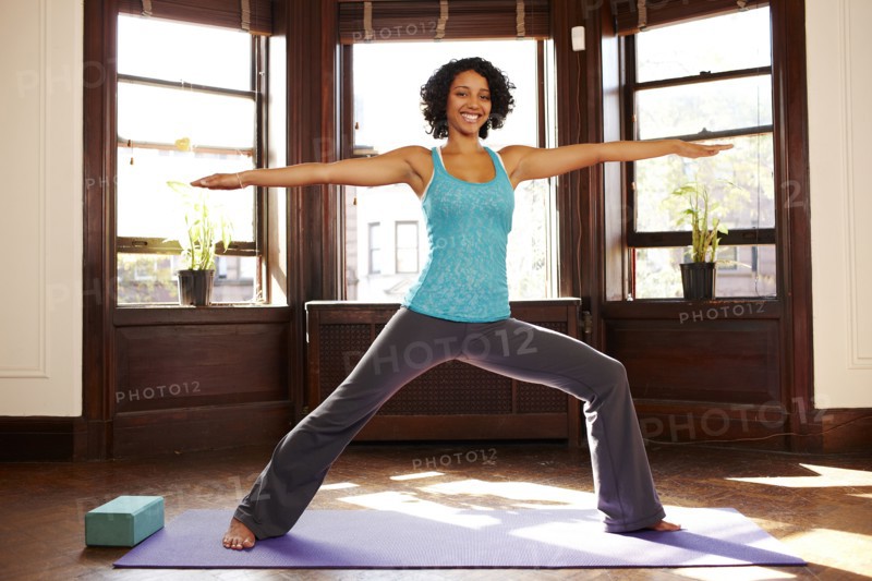 Mixed race woman practicing yoga in living room