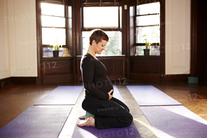 Pregnant woman sitting on yoga mat