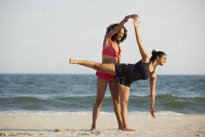 Women practicing yoga on beach