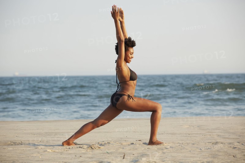 Black woman practicing yoga on beach