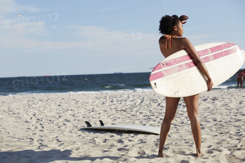 Mixed race woman carrying surfboard on beach
