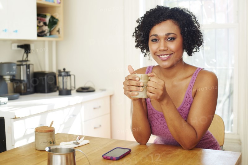 Mixed race woman drinking coffee in kitchen