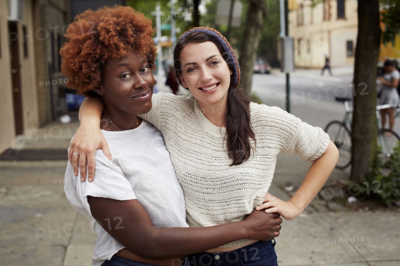 Women hugging on city street