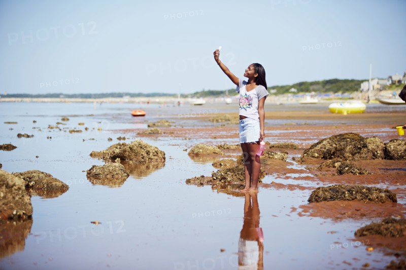 Black teenage girl taking selfie on beach