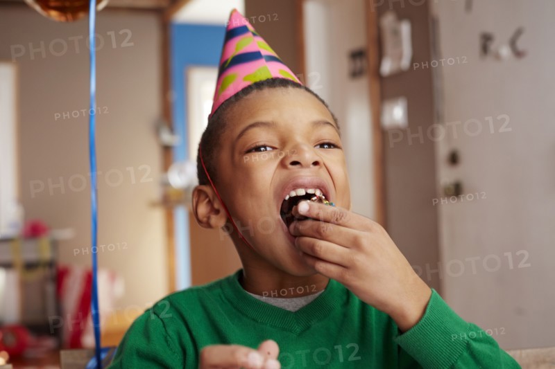 Black boy eating cake at party