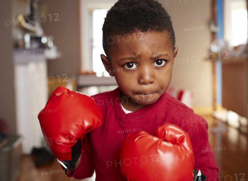 Black boy posing with boxing gloves in living room