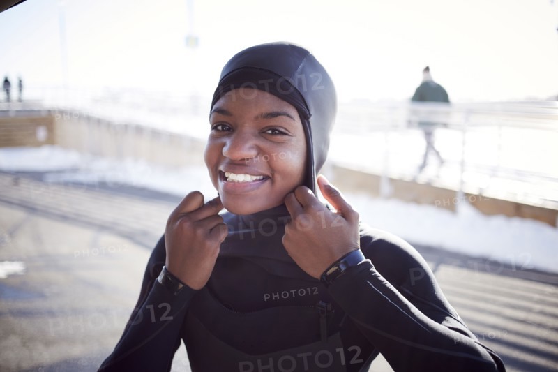 Black teenage girl putting on wetsuit swimming cap