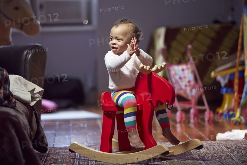 Mixed race baby girl playing on rocking horse