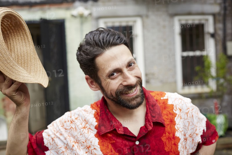 Caucasian man tipping straw hat in backyard