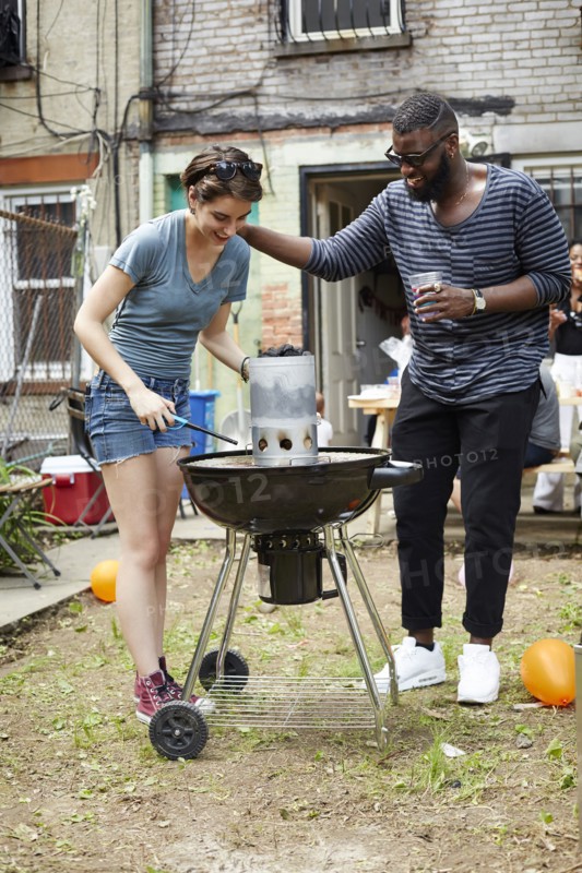 Couple lighting charcoal for backyard barbecue