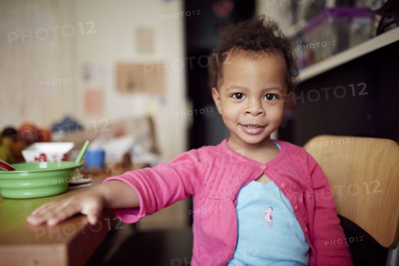 Mixed race baby girl sitting at table