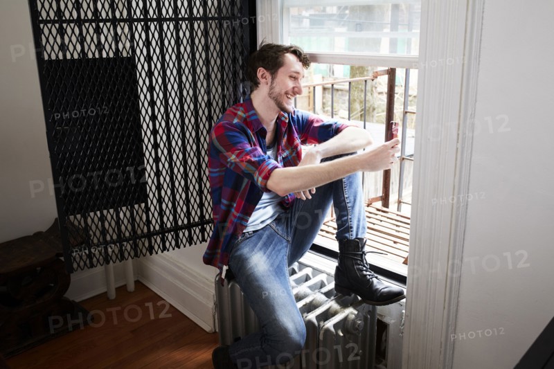 Caucasian man using cell phone in window