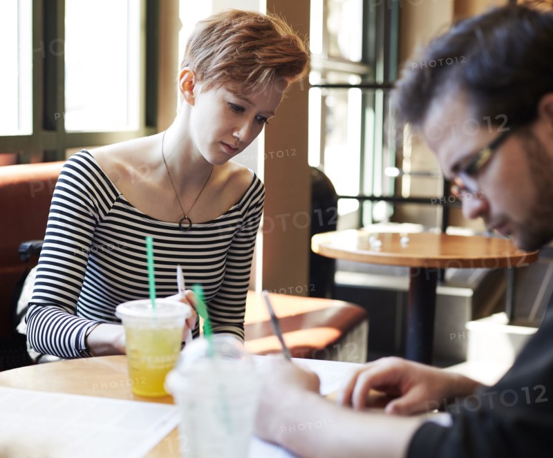Caucasian couple writing at table in cafe