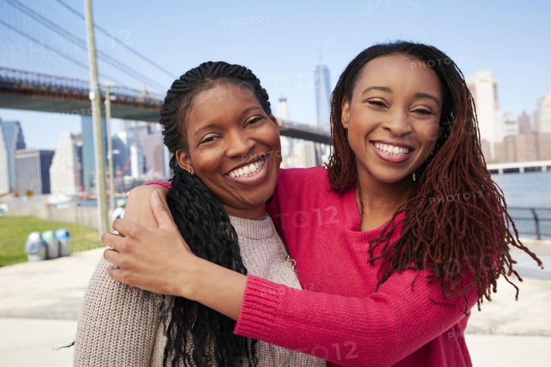 Black women hugging at waterfront