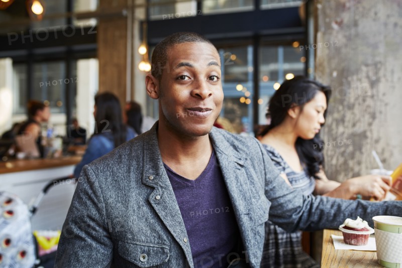 Smiling man with coffee and cupcake at coffee shop