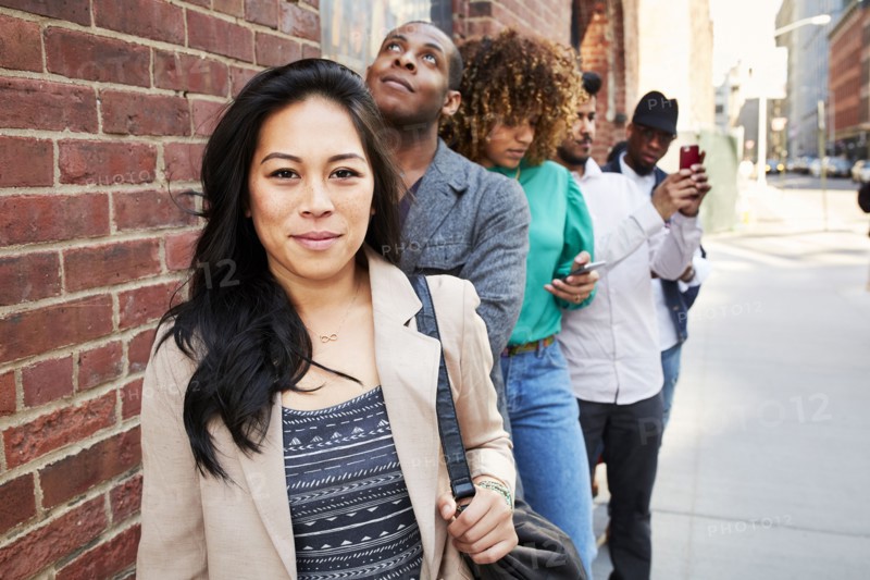 People waiting in line on sidewalk with cell phones