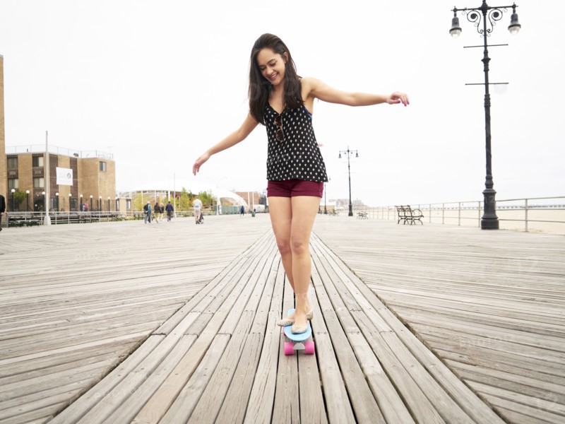 Mixed Race woman riding skateboard on boardwalk