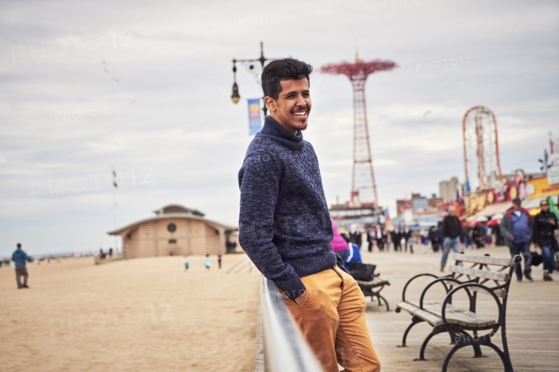 Man leaning on boardwalk railing at beach