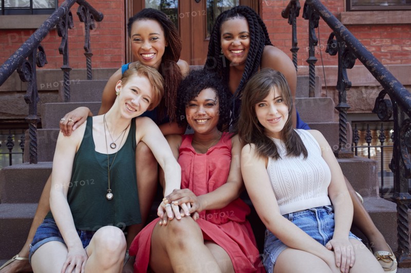 Smiling women sitting on urban front stoop