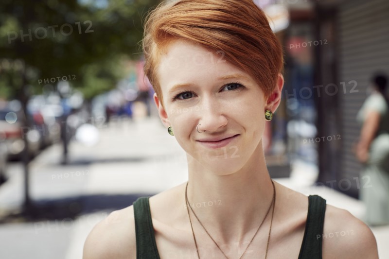 Caucasian woman with nose ring smiling on city sidewalk