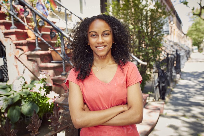 Smiling Mixed Race woman posing on city sidewalk