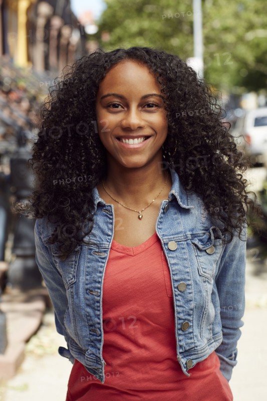 Smiling Mixed Race woman posing on city sidewalk