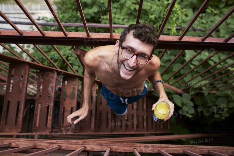 Caucasian man standing on urban fire escape drinking orange juice