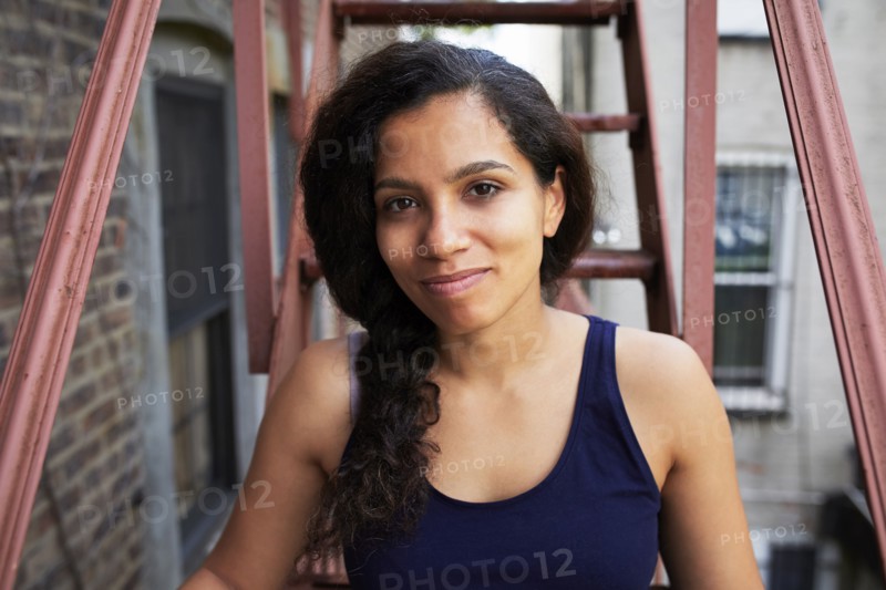 Portrait of smiling woman sitting on urban fire escape
