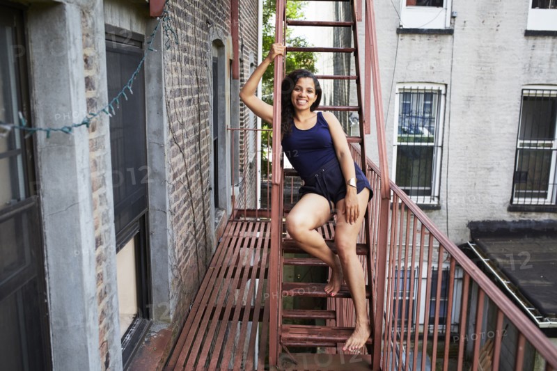 Portrait of smiling woman sitting on urban fire escape
