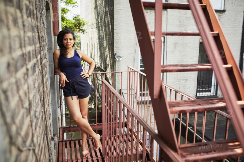 Portrait of smiling woman standing on urban fire escape