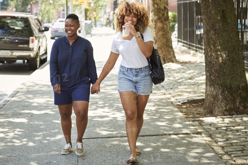 Black women holding hands on city sidewalk