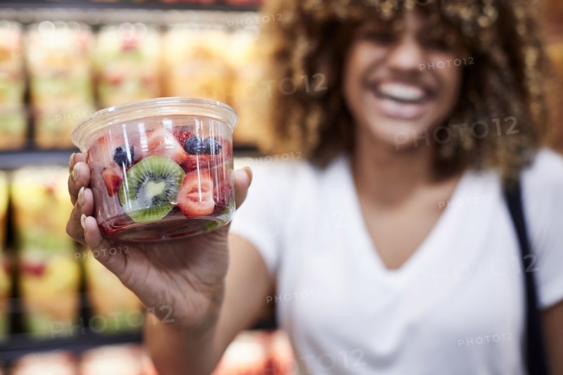 Black woman cup of fruit salad in grocery store