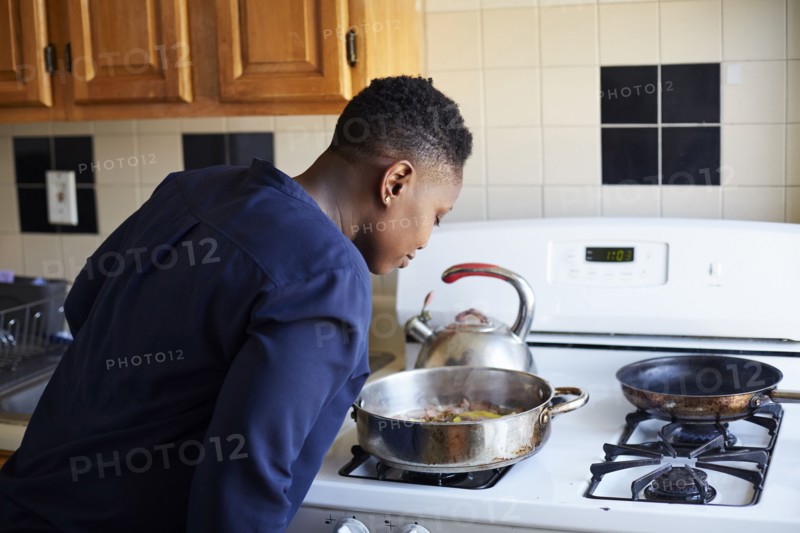 Black woman smelling food cooking in pan on stove